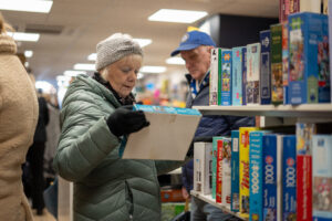 Female shopper holding puzzle next to shelves of puzzles
