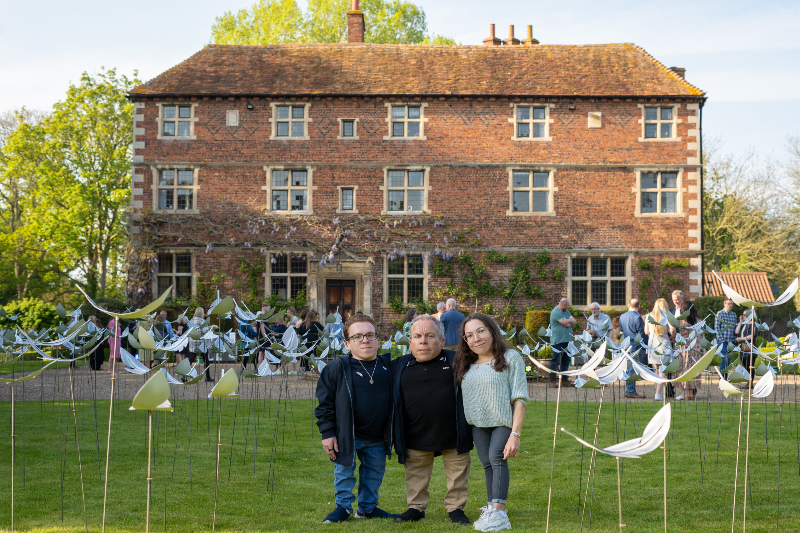 Warwick Davis and children stood in front of the Feathers from Above display and Aubourn Hall