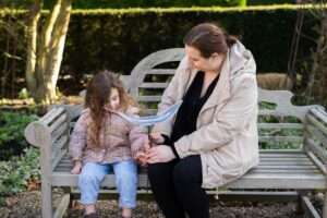 Rebekah Watson holding feather sat on bench with her daughter.