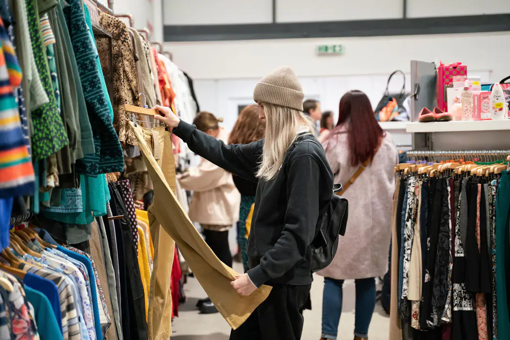 A blonde woman shopping in The Warehouse, holding up a pair of jeans